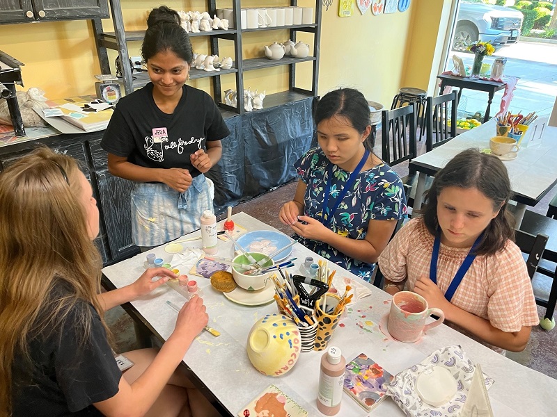Students decorating personalized pottery art projects